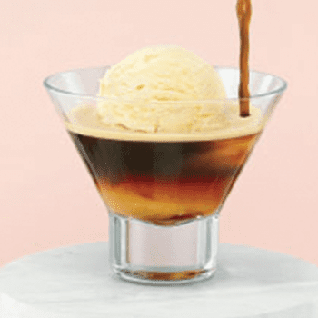 Ice cream in a glass with dark soda being poured over it